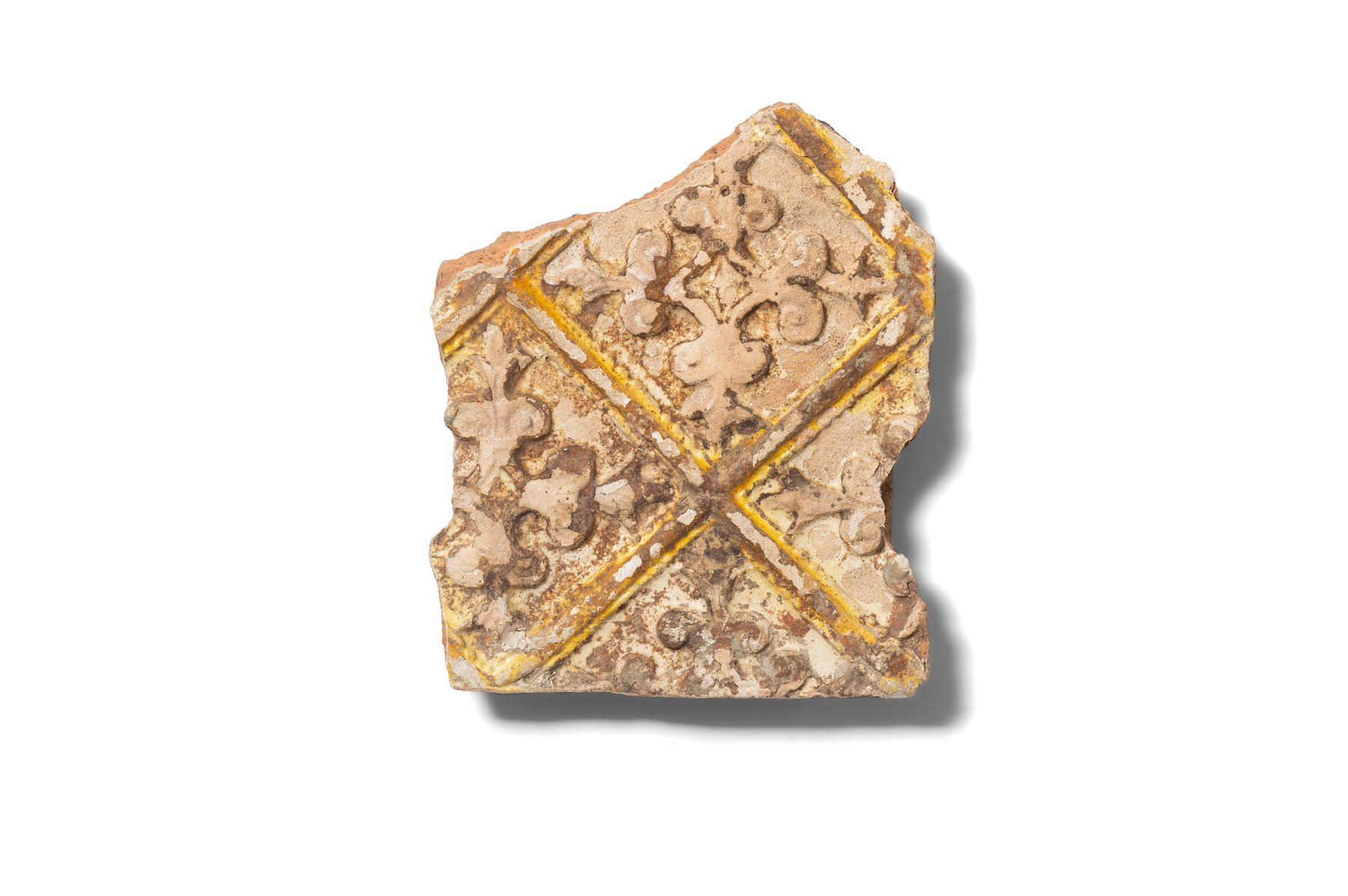 Fragment of a stove tile, referred to as a tapestry tile, decorated with a fleur-de-lis motif. Lilies are arranged in the form of a cross and framed within a diamond. The tile is made of hard, finely levigated clay and covered with yellow, white, and brown glaze. Second half of the 16th–17th century.
